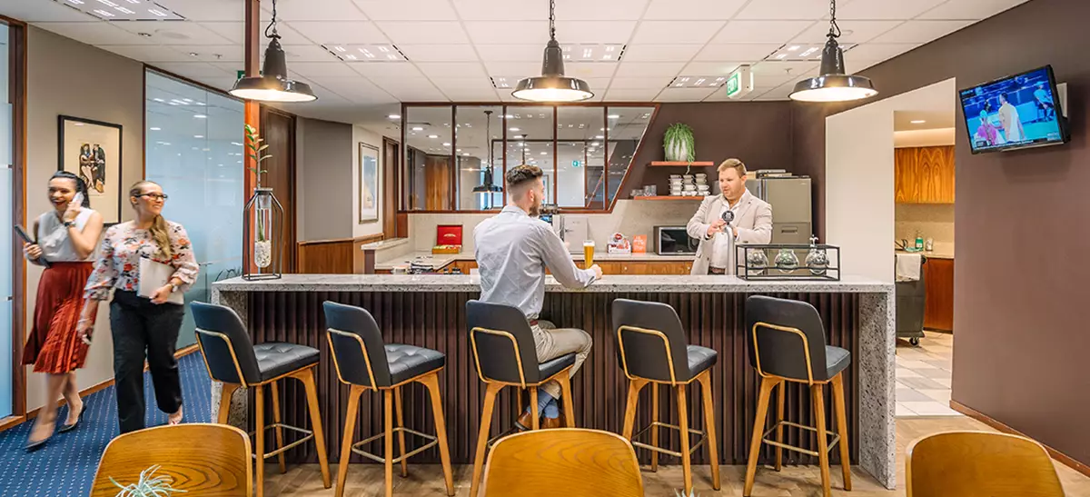 Clients enjoying coffee and networking in a fully stocked kitchen.