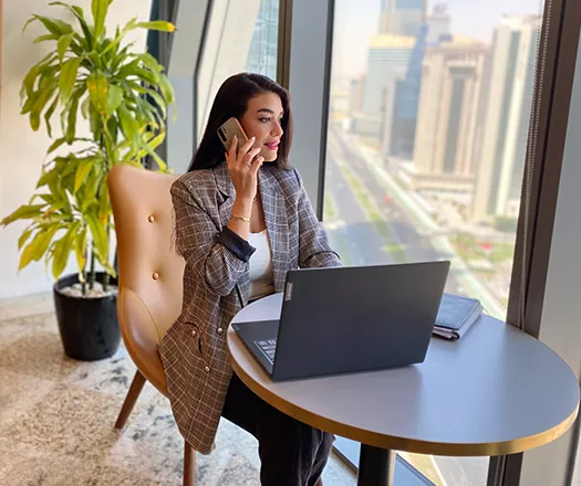 Client taking calls at a hot desk with a stunning city view in the coworking space at Tornado Tower.